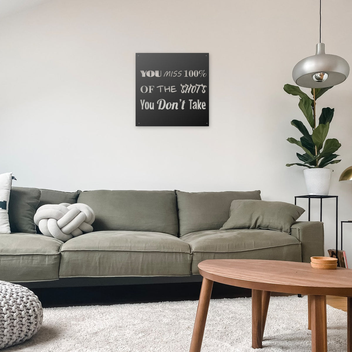 Motivational steel sign, about 24 x 24 in, hung over a sofa in a living room